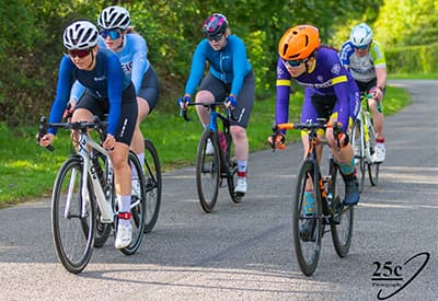 A group of four female and one male cyclists in a race on an asphalt road