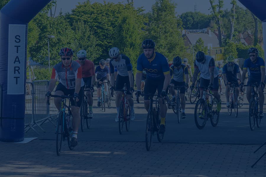 Cyclists starting a sportive. They are cycling under an inflatable arch.